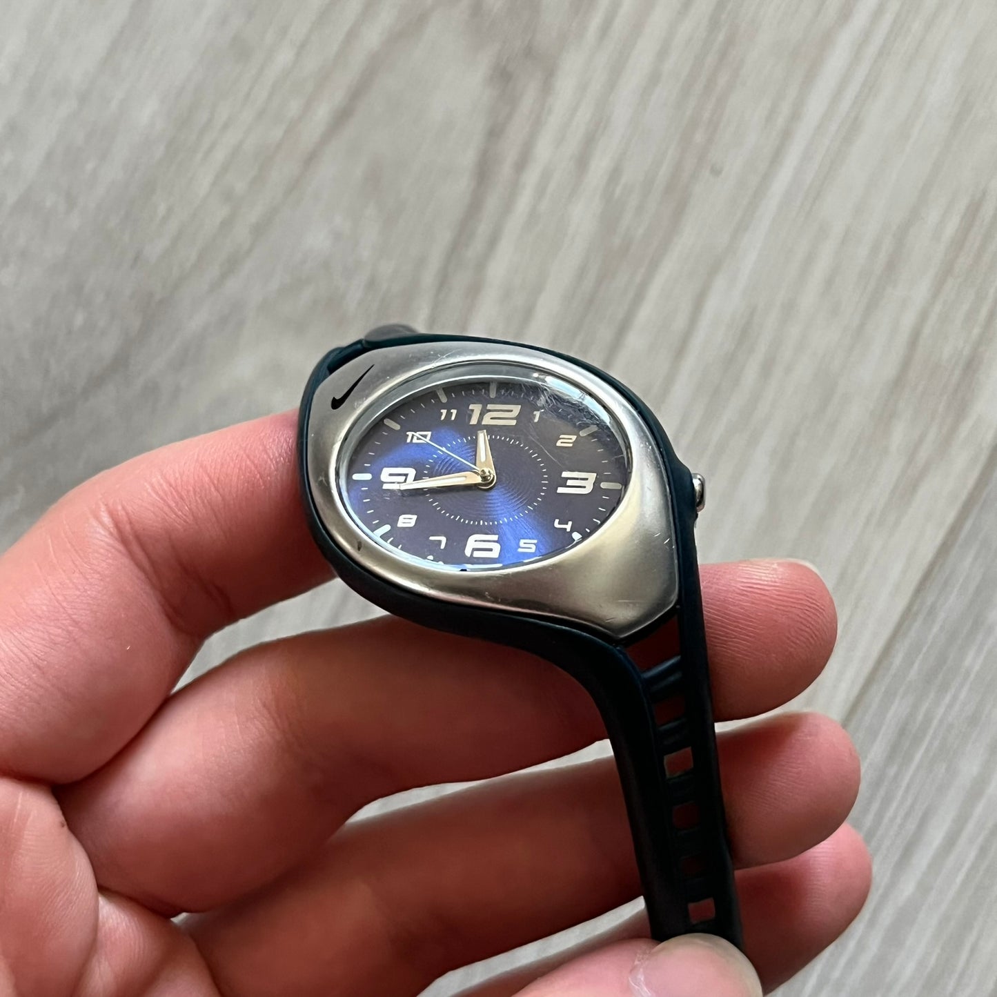 Nike Triax Roar Junior WK0007 analog watch featuring a navy rubber strap with matching navy case sides and a silver-tone front case. The metallic blue dial has a high-shine finish, silver hour markers, and silver hands for clear visibility. Built with stainless steel and metal components, the watch is water resistant up to 50 meters