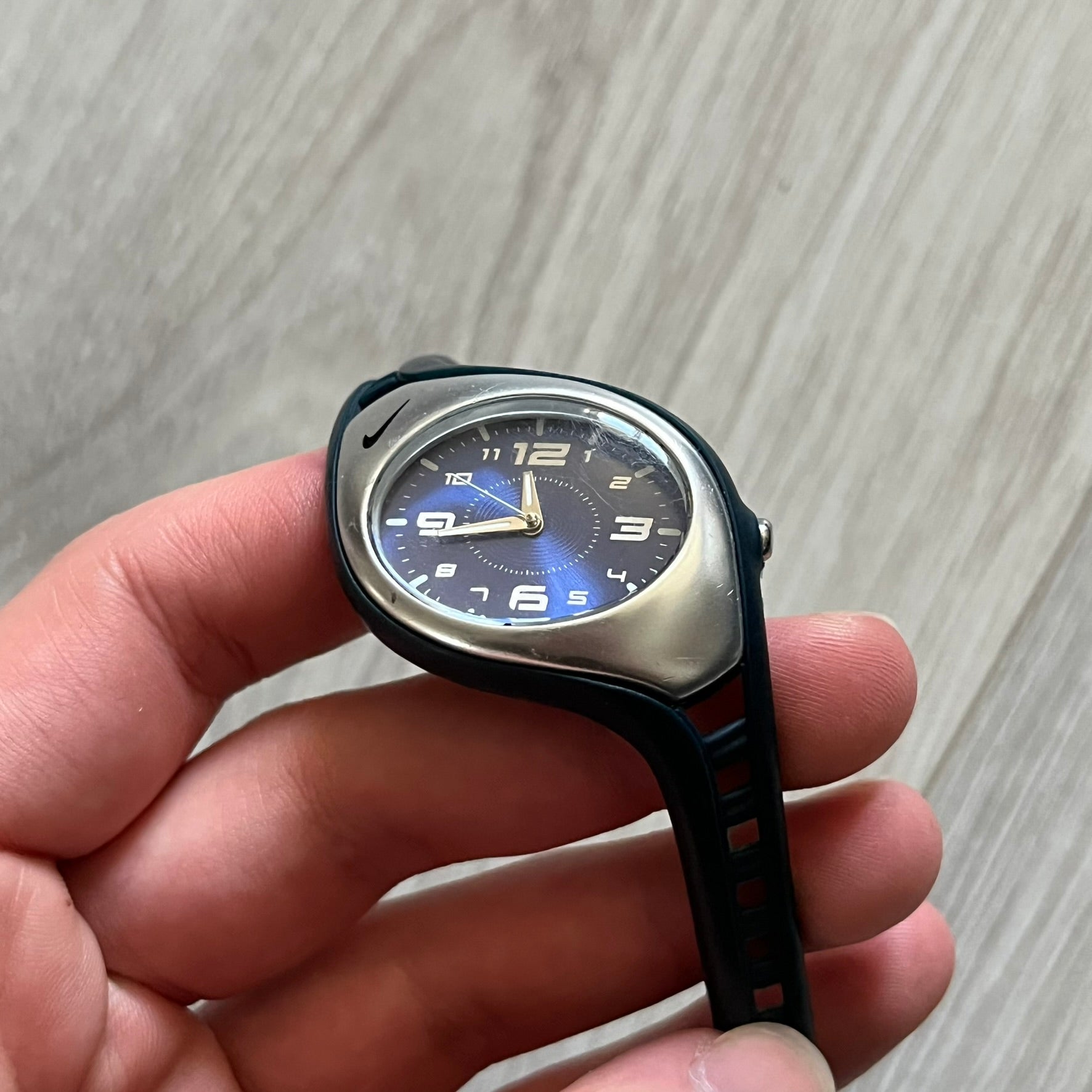Nike Triax Roar Junior WK0007 analog watch featuring a navy rubber strap with matching navy case sides and a silver-tone front case. The metallic blue dial has a high-shine finish, silver hour markers, and silver hands for clear visibility. Built with stainless steel and metal components, the watch is water resistant up to 50 meters