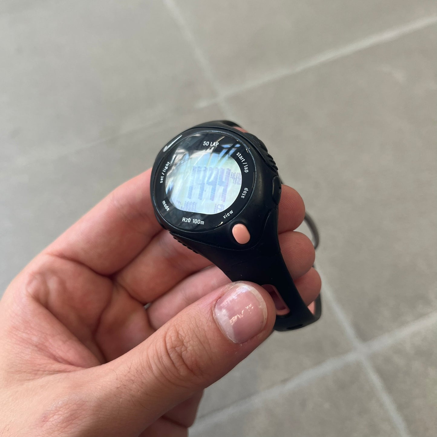 Nike Triax Speed 50 Regular Pink Digital Watch features a black case with four black side buttons and a pink-ish front button for the backlight function. The watch has an white Nike Swoosh on the top of the case, 50-lap memory, multiple modes, and 100m water resistance.