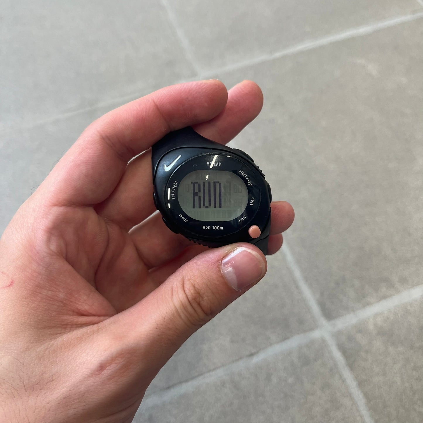 Nike Triax Speed 50 Regular Pink Digital Watch features a black case with four black side buttons and a pink-ish front button for the backlight function. The watch has an white Nike Swoosh on the top of the case, 50-lap memory, multiple modes, and 100m water resistance.