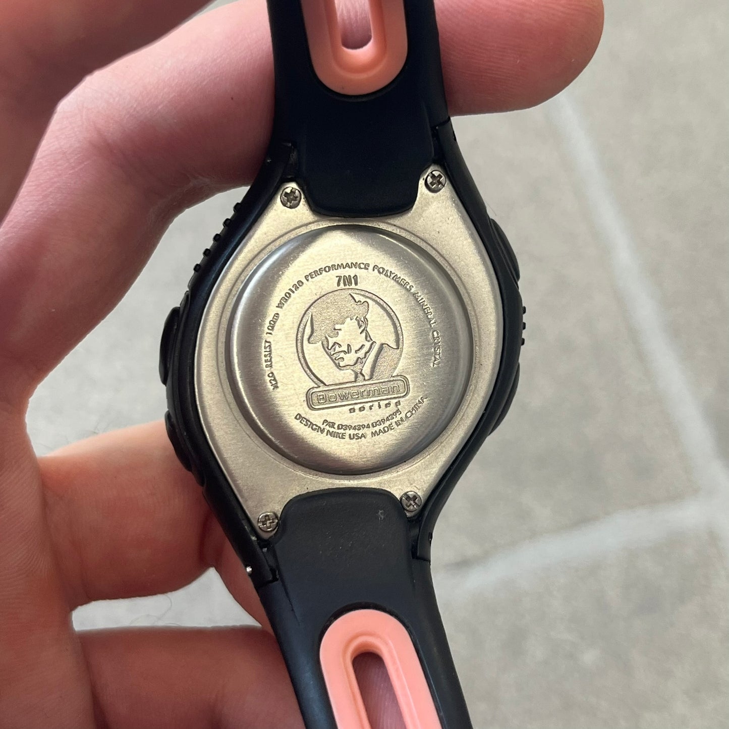 Nike Triax Speed 50 Regular Pink Digital Watch features a black case with four black side buttons and a pink-ish front button for the backlight function. The watch has an white Nike Swoosh on the top of the case, 50-lap memory, multiple modes, and 100m water resistance.