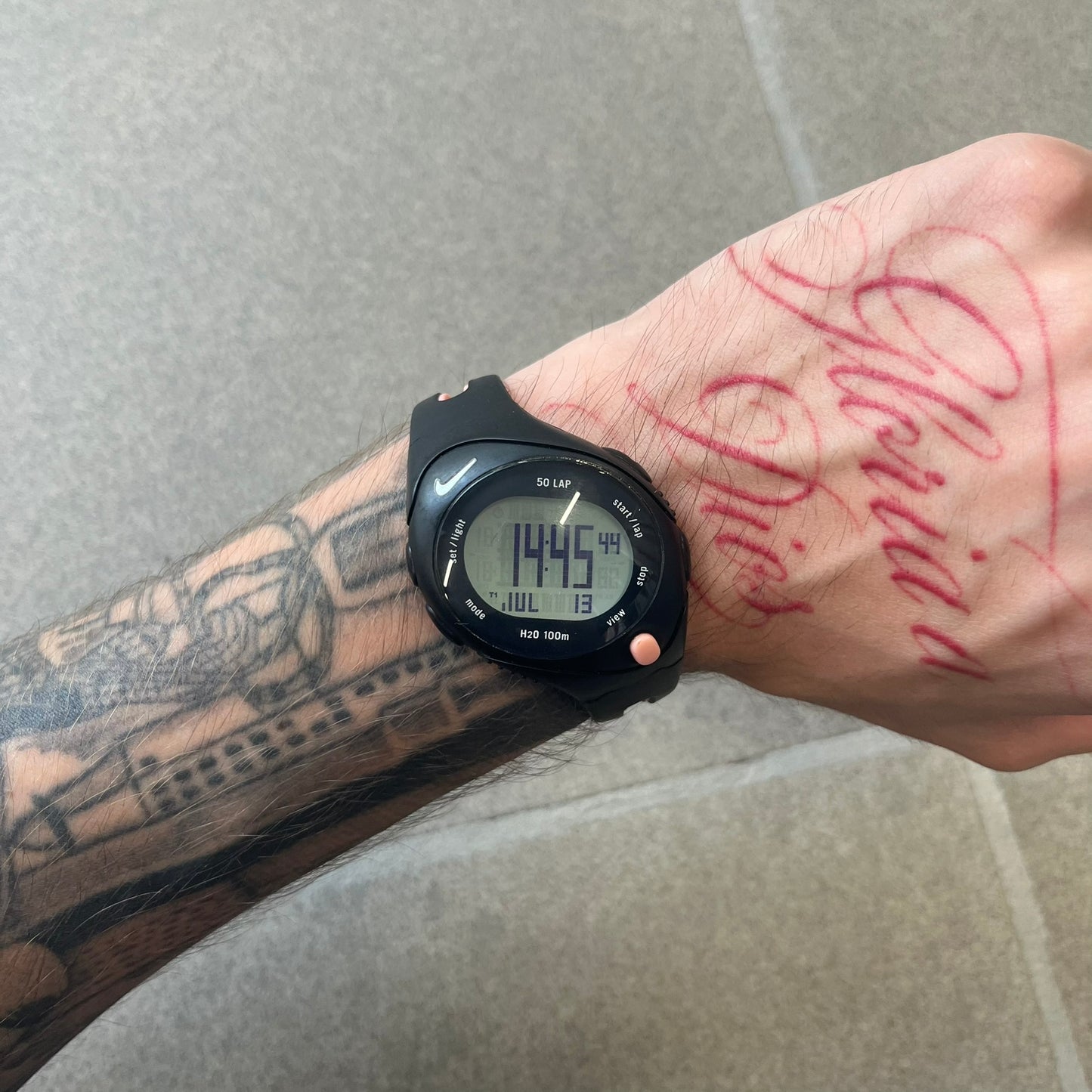 Nike Triax Speed 50 Regular Pink Digital Watch features a black case with four black side buttons and a pink-ish front button for the backlight function. The watch has an white Nike Swoosh on the top of the case, 50-lap memory, multiple modes, and 100m water resistance.