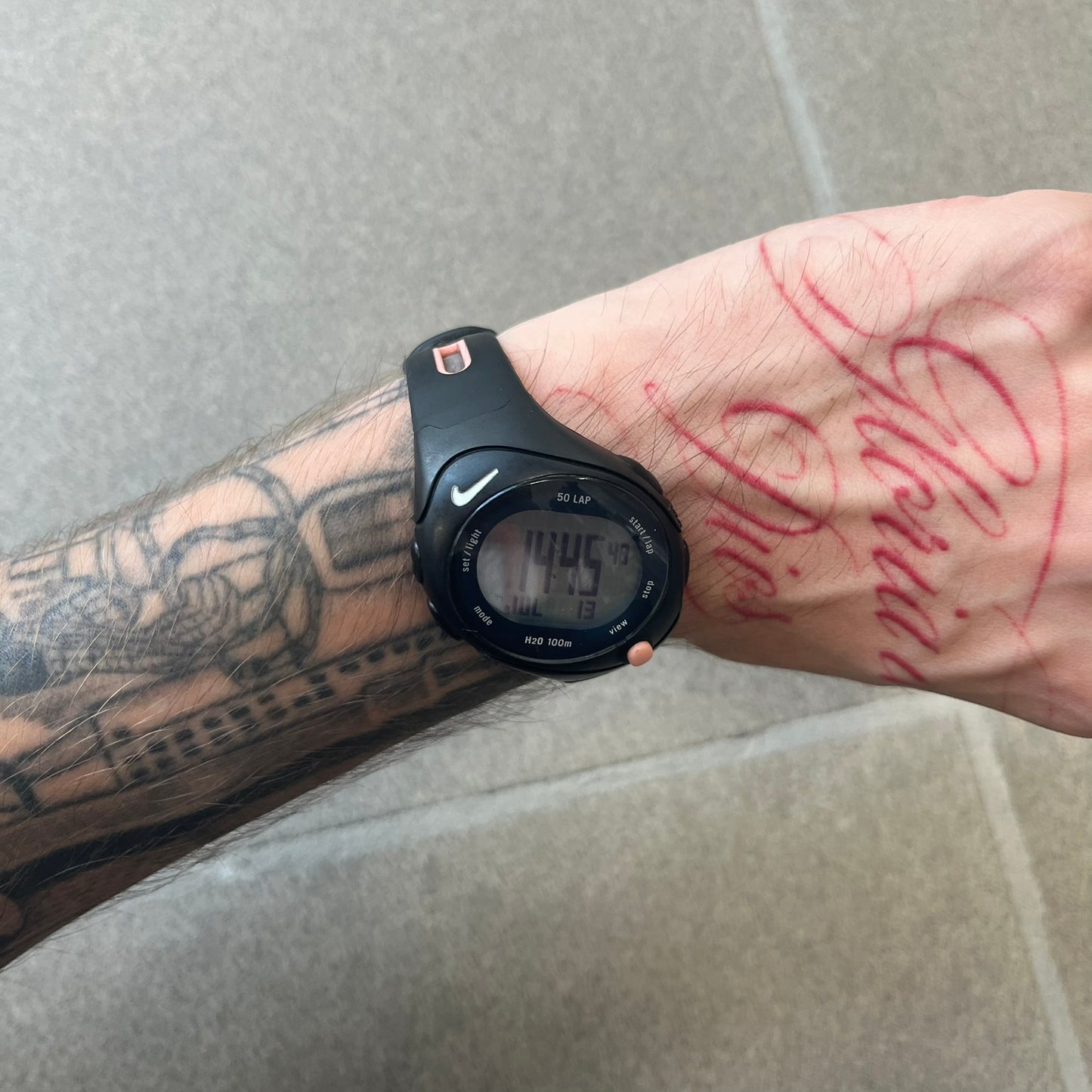 Nike Triax Speed 50 Regular Pink Digital Watch features a black case with four black side buttons and a pink-ish front button for the backlight function. The watch has an white Nike Swoosh on the top of the case, 50-lap memory, multiple modes, and 100m water resistance.