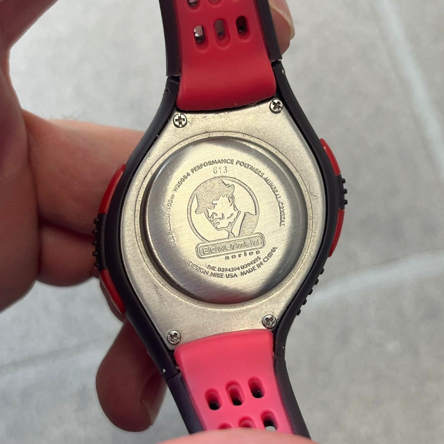 Nike Triax Speed 100 Regular Red Digital Watch features a silver-tone case with four red side buttons and a front button for the backlight function. The watch has an black Nike Swoosh on the top of the case, 100-lap memory, multiple modes, and 100m water resistance. It comes with brown-ish bracelet.
