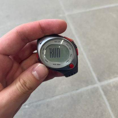Nike Triax Speed 100 Regular Red Digital Watch features a silver-tone case with four red side buttons and a front button for the backlight function. The watch has an black Nike Swoosh on the top of the case, 100-lap memory, multiple modes, and 100m water resistance. It comes with brown-ish bracelet.
