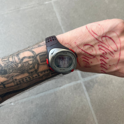 Nike Triax Speed 100 Regular Red Digital Watch features a silver-tone case with four red side buttons and a front button for the backlight function. The watch has an black Nike Swoosh on the top of the case, 100-lap memory, multiple modes, and 100m water resistance. It comes with brown-ish bracelet.
