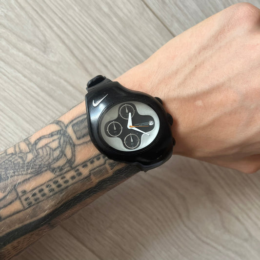 Black smartwatch on a wrist with tattoos, on a light-colored surface