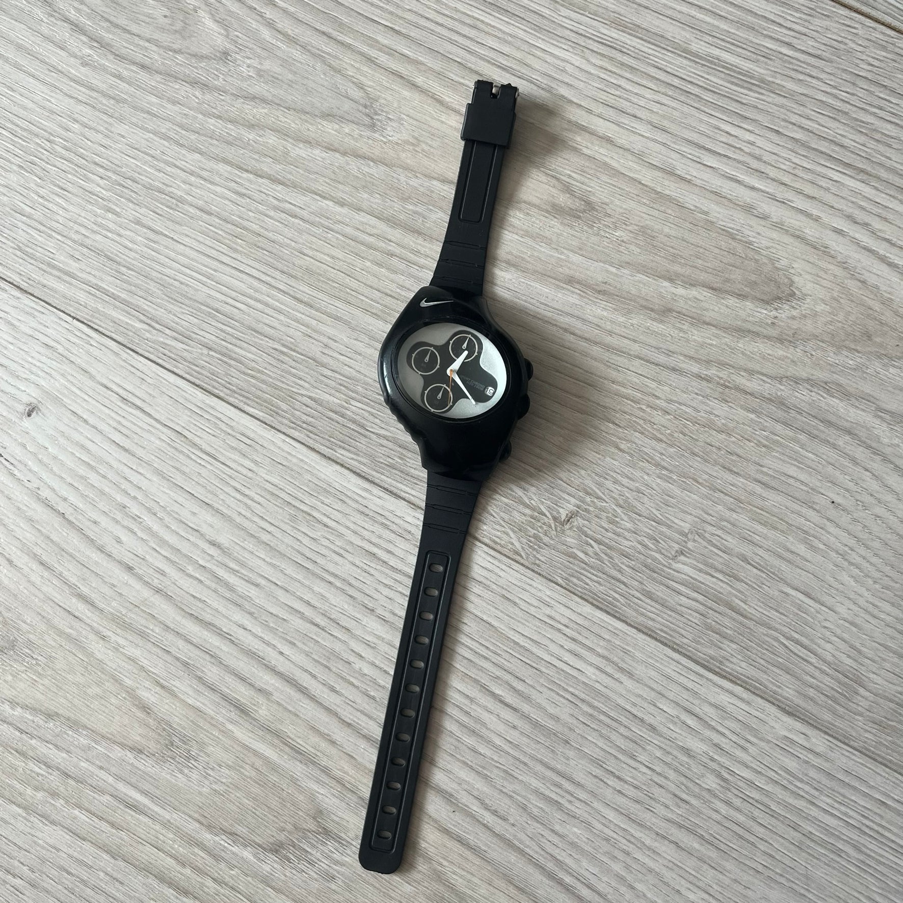 Black wristwatch with a unique face design on a gray surface