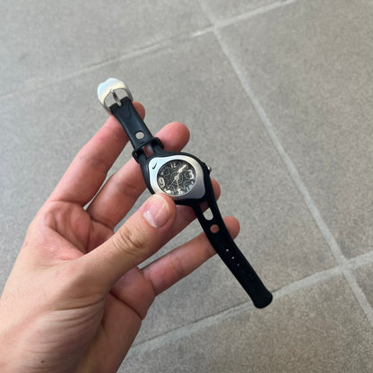 Nike Triax Sweeper is a really small analog watch that features a compact silver-tone case with a black Nike Swoosh at the top. It has black rubber straps and a black dial with white hour markers and decorative star and dot graphics. The watch is water resistant to 50 metres.