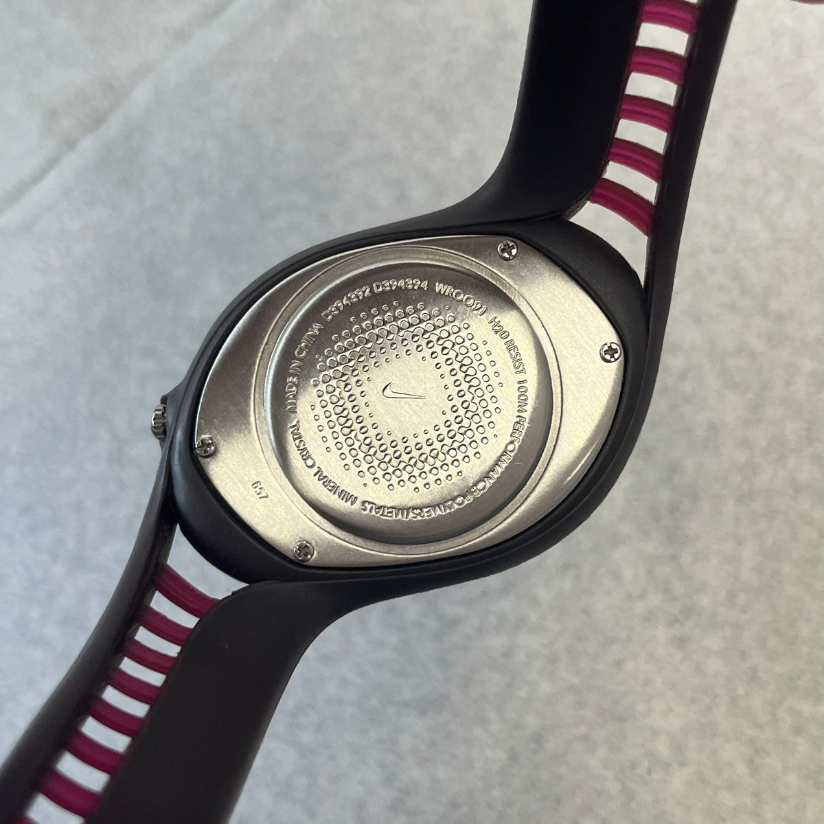 Nike Triax Swift 3i Burgundy WR0091 Analog Watch comes with burgundy and red rubber straps and a silver case featuring a dark Nike Swoosh. The burgundy metallic dial has a dotted pattern, three silver subdials for day, date, and hour and silver hands. Seconds markings are printed on the inner edge of the case and are visible only at an angle.