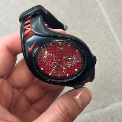 Nike Triax Swift 3i Red WR0091 Analog Watch comes with black &amp; red rubber straps and a black case featuring a red Nike Swoosh. The red metallic dial has a woven pattern, three silver subdials for day, date, and hour and silver hands. Seconds markings are printed on the inner edge of the case and are visible only at an angle. Sport-focused Triax case design with water-resistant construction.