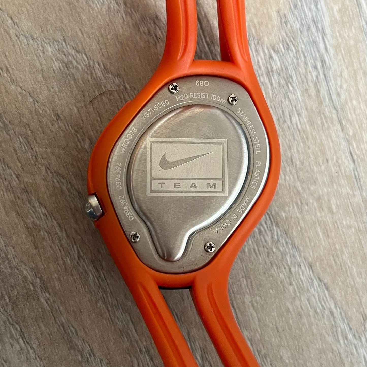 Nike Triax Swift Illinois University WR0078 Analog Watch is a sports watch featuring an integrated one-piece construction with orange straps and navy accents. The dark navy stainless steel case includes a white Nike Swoosh and a white button that activates the light blue backlight. The orange dial features the large Illinois University “I” logo. Made from stainless steel and plastic materials, the watch is water resistant up to 100 meters.