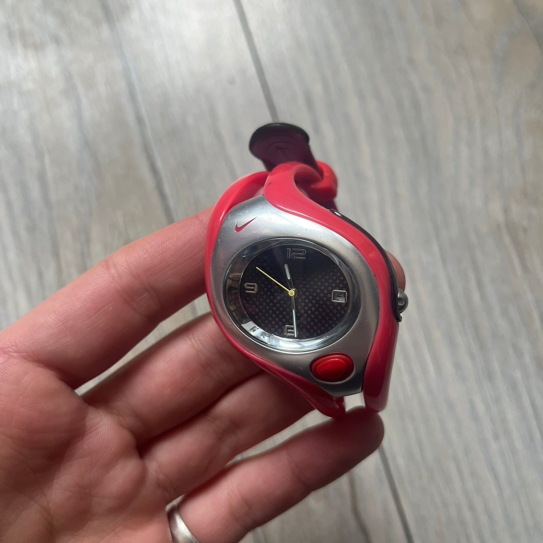 Nike Triax Swift WR0078 analog wristwatch with pink rubber straps and a matching rubber outer case. The internal case is silver-tone metal, fitted with a pink front button and pink Nike Swoosh branding. Features a black dotted dial with silver hands and markers. Sport-oriented construction with a clean, functional layout typical of early-2000s Nike Triax models.