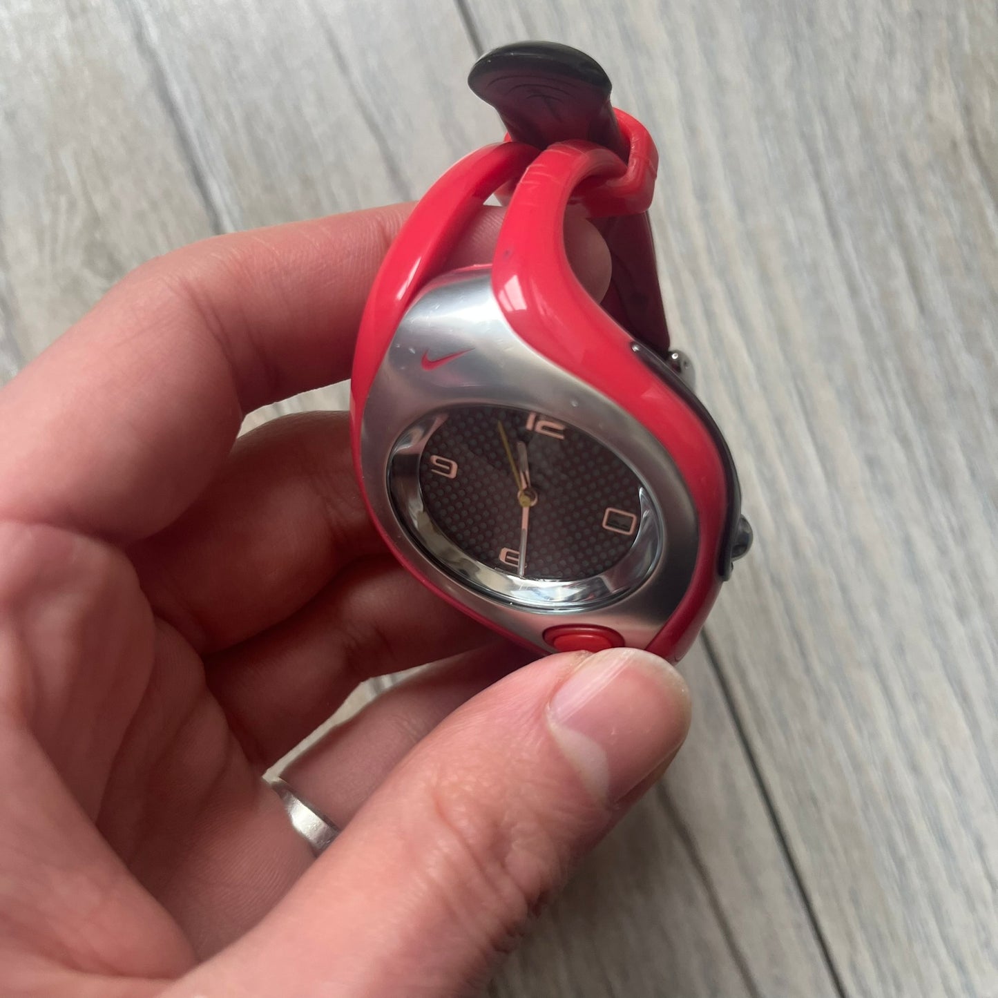 Nike Triax Swift WR0078 analog wristwatch with pink rubber straps and a matching rubber outer case. The internal case is silver-tone metal, fitted with a pink front button and pink Nike Swoosh branding. Features a black dotted dial with silver hands and markers. Sport-oriented construction with a clean, functional layout typical of early-2000s Nike Triax models.