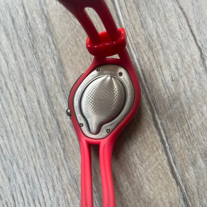 Nike Triax Swift WR0078 analog wristwatch with pink rubber straps and a matching rubber outer case. The internal case is silver-tone metal, fitted with a pink front button and pink Nike Swoosh branding. Features a black dotted dial with silver hands and markers. Sport-oriented construction with a clean, functional layout typical of early-2000s Nike Triax models.