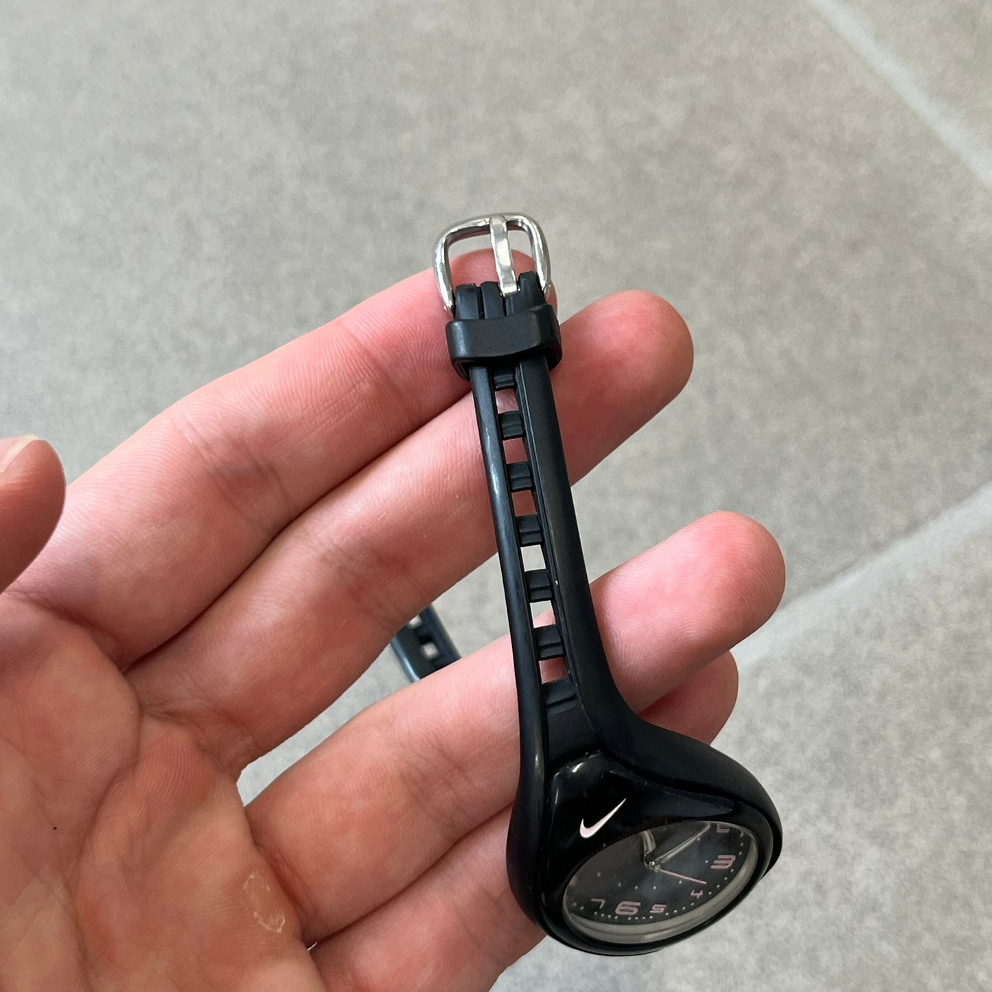 Nike Triax Swift WK0007 Black &amp; Pink Analog Watch features a black rubber strap with matching front case. The black dial has pink hour markers, and silver hands. Small Pink Nike logo sits above the case. Built with stainless steel and metal components, the watch is water resistant up to 50 meters.