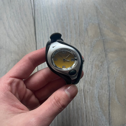 Nike Triax Swift WR0078 analog wristwatch with black rubber straps and a matching rubber outer case. The internal case is silver-tone metal, fitted with a black side button and black Nike Swoosh branding. Features a yellow dotted dial with silver hands and markers. Sport-oriented construction with a clean, functional layout typical of early-2000s Nike Triax models.