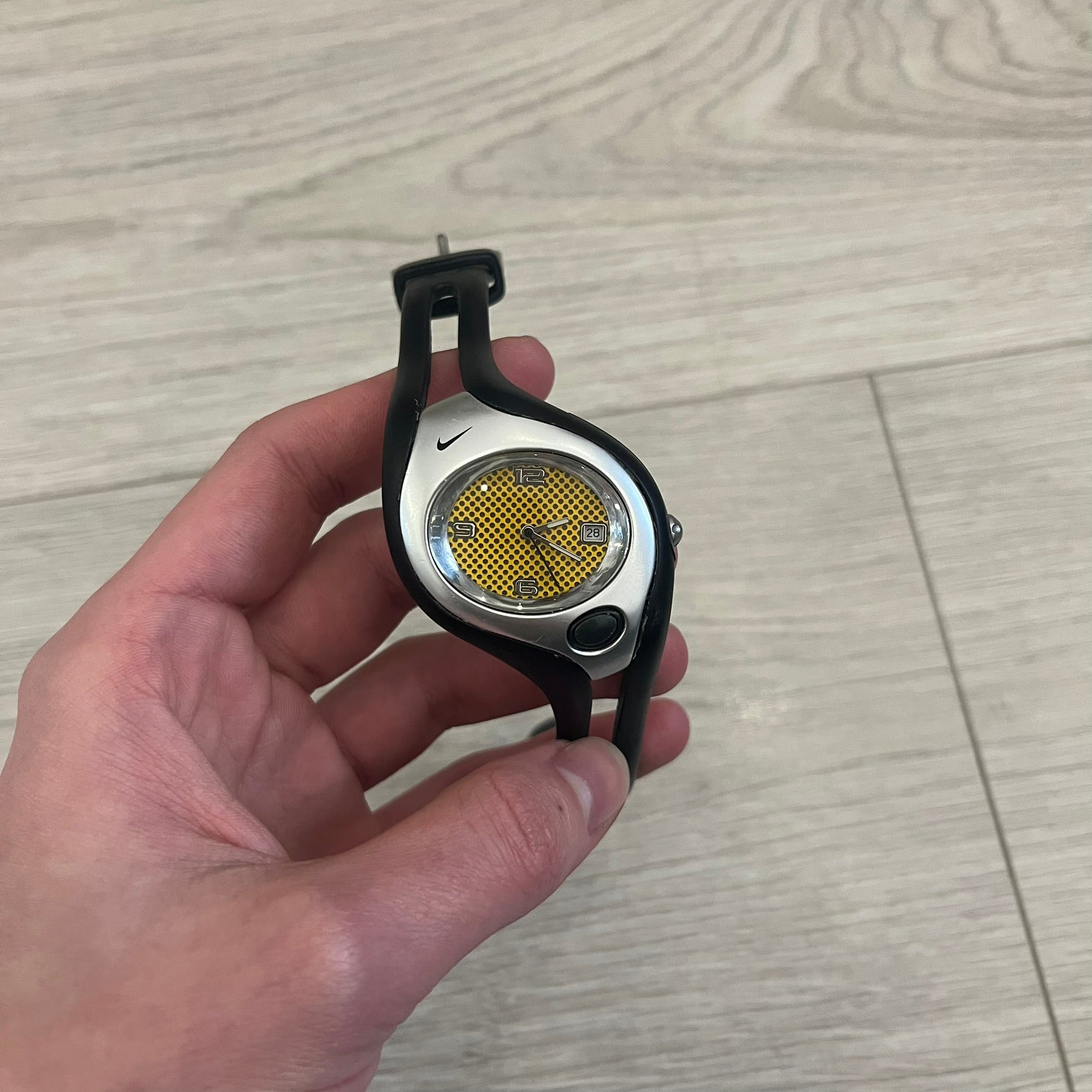 Nike Triax Swift WR0078 analog wristwatch with black rubber straps and a matching rubber outer case. The internal case is silver-tone metal, fitted with a black side button and black Nike Swoosh branding. Features a yellow dotted dial with silver hands and markers, paired with an integrated turquoise backlight that illuminates the face when activated. Sport-oriented construction with a clean, functional layout typical of early-2000s Nike Triax models.&nbsp;