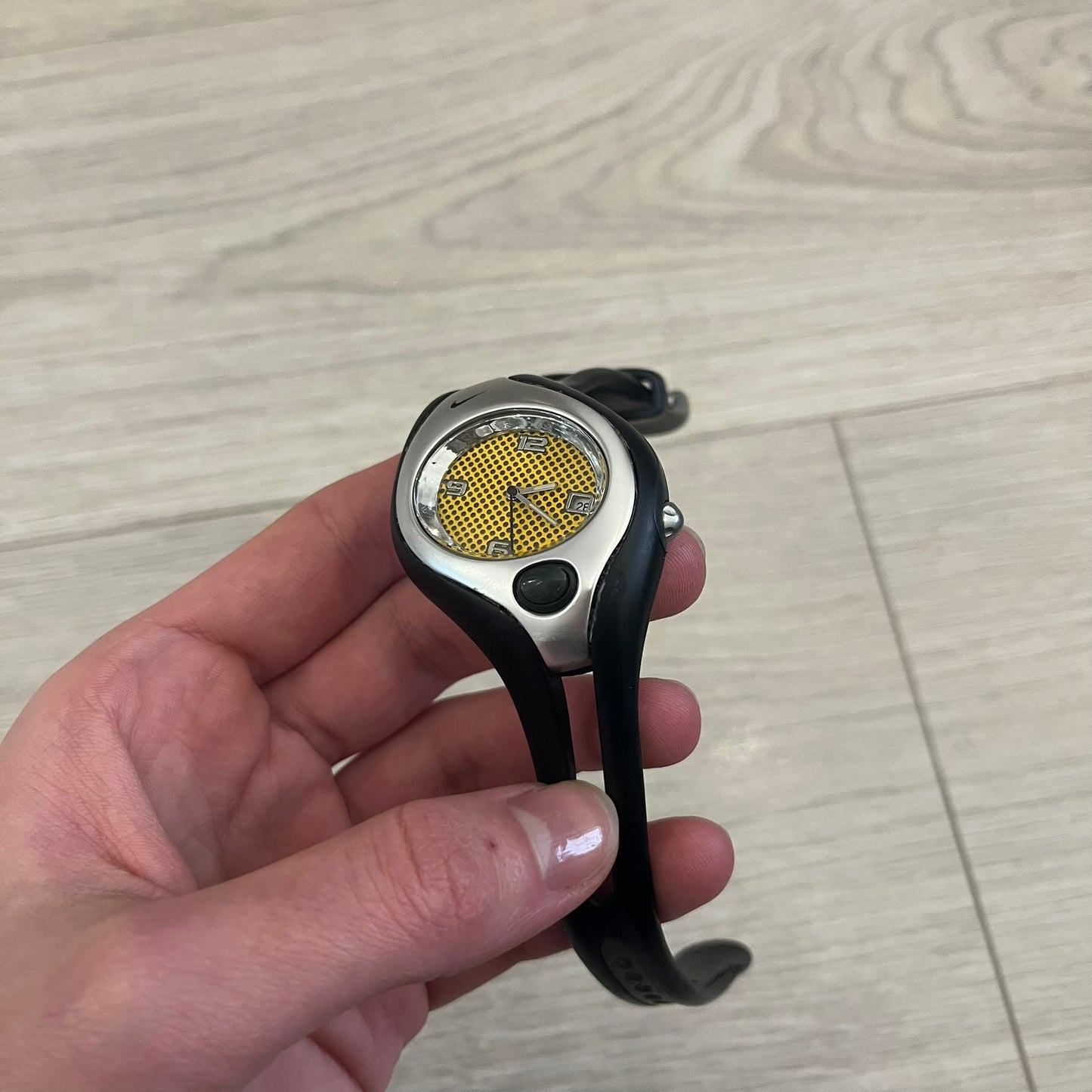 Nike Triax Swift WR0078 analog wristwatch with black rubber straps and a matching rubber outer case. The internal case is silver-tone metal, fitted with a black side button and black Nike Swoosh branding. Features a yellow dotted dial with silver hands and markers, paired with an integrated turquoise backlight that illuminates the face when activated. Sport-oriented construction with a clean, functional layout typical of early-2000s Nike Triax models.&nbsp;