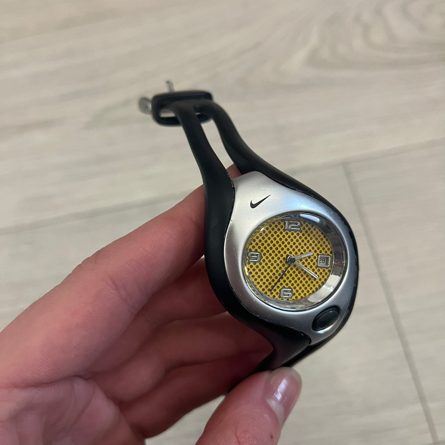Nike Triax Swift WR0078 analog wristwatch with black rubber straps and a matching rubber outer case. The internal case is silver-tone metal, fitted with a black side button and black Nike Swoosh branding. Features a yellow dotted dial with silver hands and markers, paired with an integrated turquoise backlight that illuminates the face when activated. Sport-oriented construction with a clean, functional layout typical of early-2000s Nike Triax models.&nbsp;