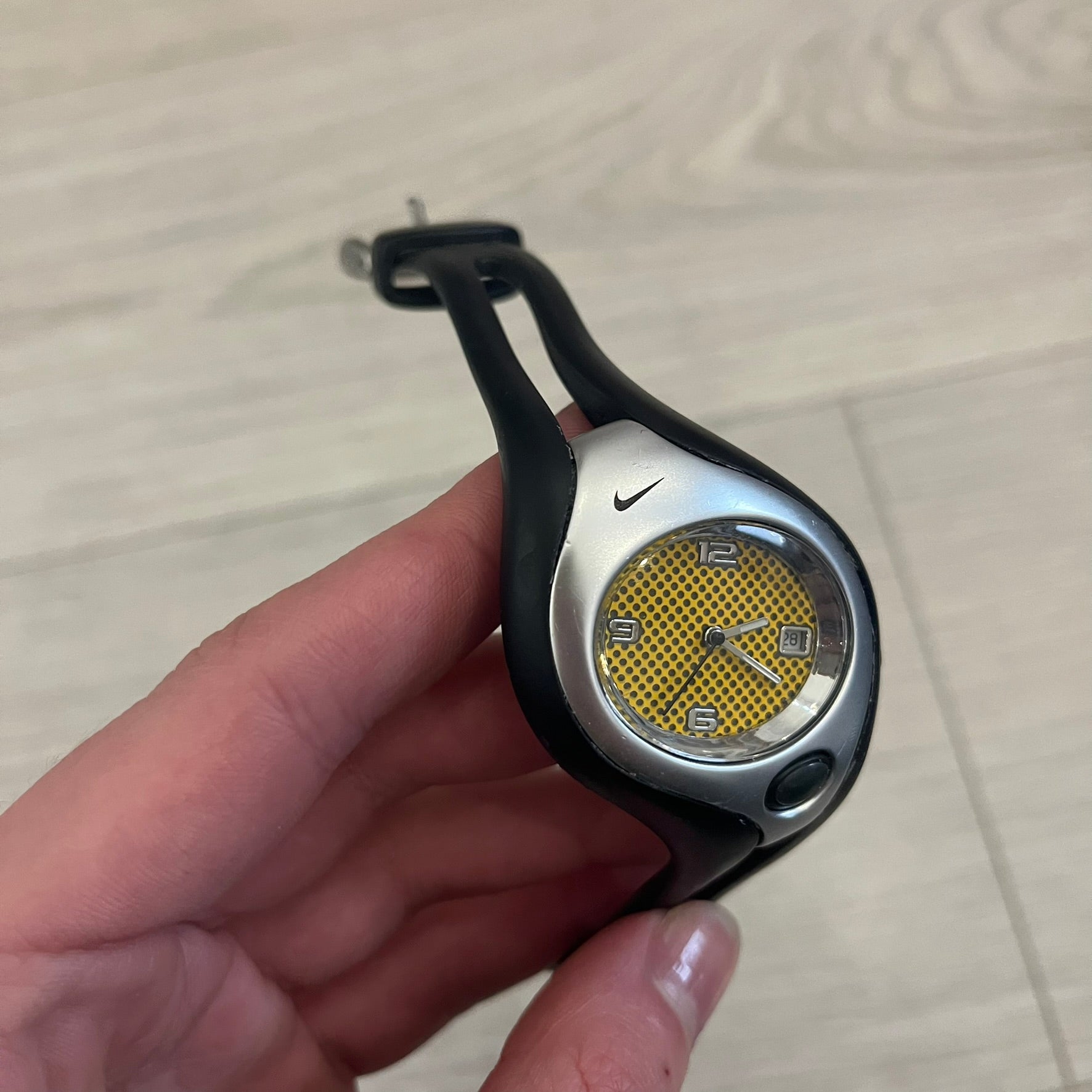 Nike Triax Swift WR0078 analog wristwatch with black rubber straps and a matching rubber outer case. The internal case is silver-tone metal, fitted with a black side button and black Nike Swoosh branding. Features a yellow dotted dial with silver hands and markers, paired with an integrated turquoise backlight that illuminates the face when activated. Sport-oriented construction with a clean, functional layout typical of early-2000s Nike Triax models.&nbsp;
