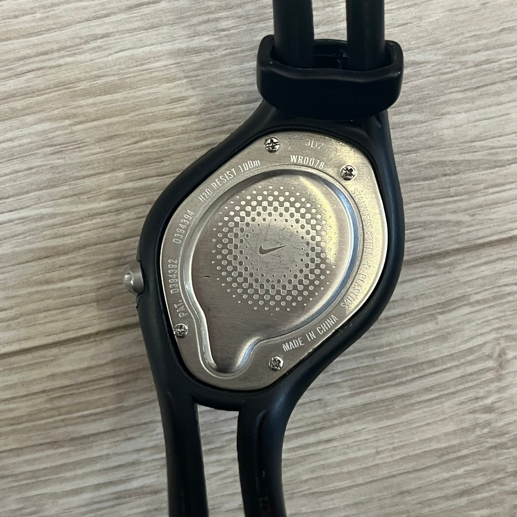 Nike Triax Swift WR0078 analog wristwatch with black rubber straps and a matching rubber outer case. The internal case is silver-tone metal, fitted with a black side button and black Nike Swoosh branding. Features a yellow dotted dial with silver hands and markers, paired with an integrated turquoise backlight that illuminates the face when activated. Sport-oriented construction with a clean, functional layout typical of early-2000s Nike Triax models.&nbsp;