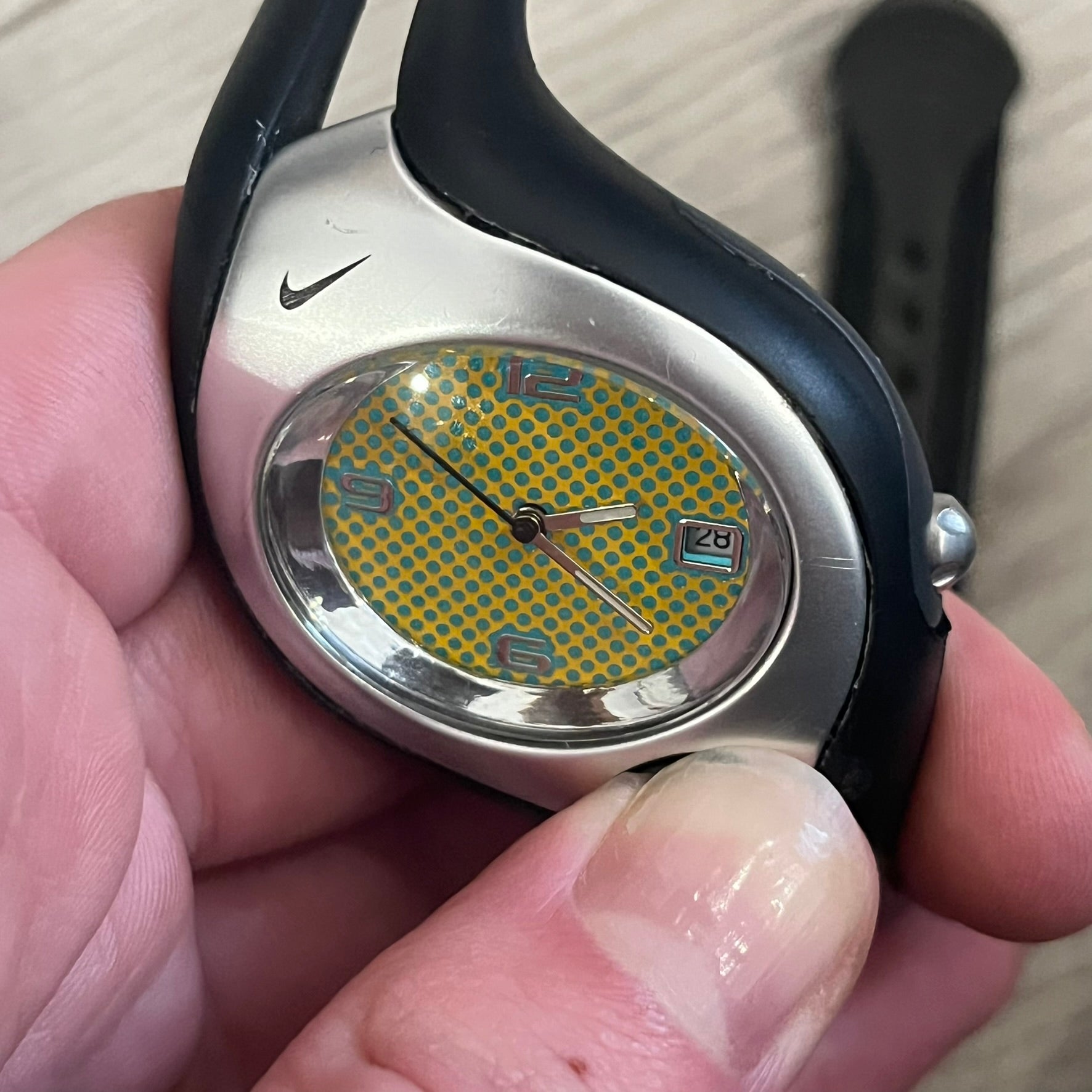 Nike Triax Swift WR0078 analog wristwatch with black rubber straps and a matching rubber outer case. The internal case is silver-tone metal, fitted with a black side button and black Nike Swoosh branding. Features a yellow dotted dial with silver hands and markers, paired with an integrated turquoise backlight that illuminates the face when activated. Sport-oriented construction with a clean, functional layout typical of early-2000s Nike Triax models.&nbsp;