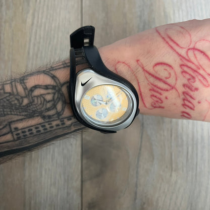 Nike Triax “Brasil” Swift 3i WR0091 analog watch with black rubber straps and a silver-tone case featuring a black Nike Swoosh. The yellow metallic dial has a recessed dotted texture, a Brazil crest at the top, three silver subdials for day, date, and hour, silver hands, and a green seconds hand. Seconds markings are printed on the inner edge of the case and are visible only at an angle. Sport-focused Triax case design with water-resistant construction.