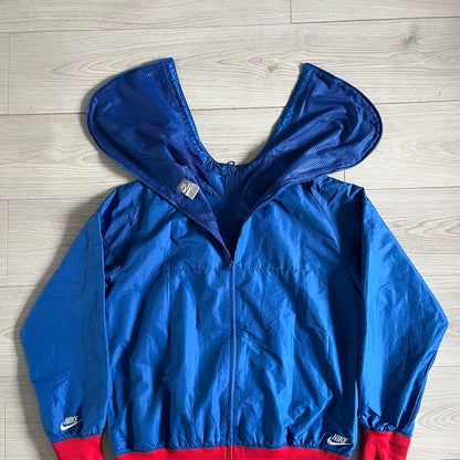 Nike UK Olympics 2008 Split Windbreaker designed by Jarrett Reynolds. Features a blue base with Union Jack-inspired red and white stripes on the front, representing Great Britain. Dual side zippers allow the jacket to be split in half and combined with other pieces from the collection, with a subtle United Kingdom flag inside the pocket.