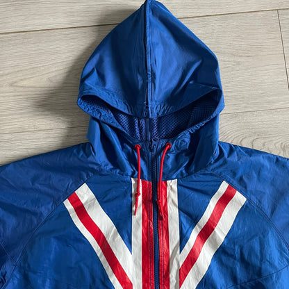 Nike UK Olympics 2008 Split Windbreaker designed by Jarrett Reynolds. Features a blue base with Union Jack-inspired red and white stripes on the front, representing Great Britain. Dual side zippers allow the jacket to be split in half and combined with other pieces from the collection, with a subtle United Kingdom flag inside the pocket.