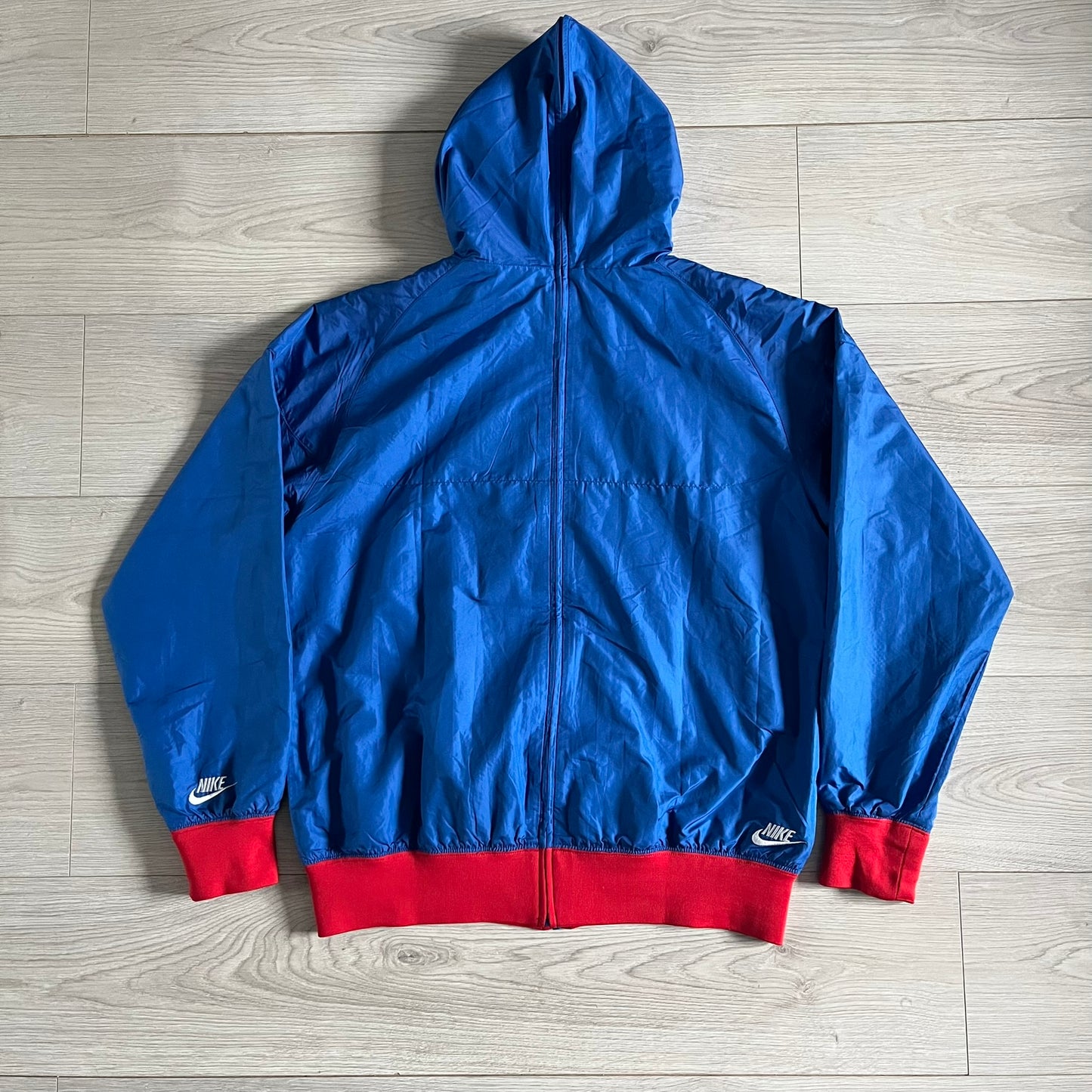 Nike UK Olympics 2008 Split Windbreaker designed by Jarrett Reynolds. Features a blue base with Union Jack-inspired red and white stripes on the front, representing Great Britain. Dual side zippers allow the jacket to be split in half and combined with other pieces from the collection, with a subtle United Kingdom flag inside the pocket.