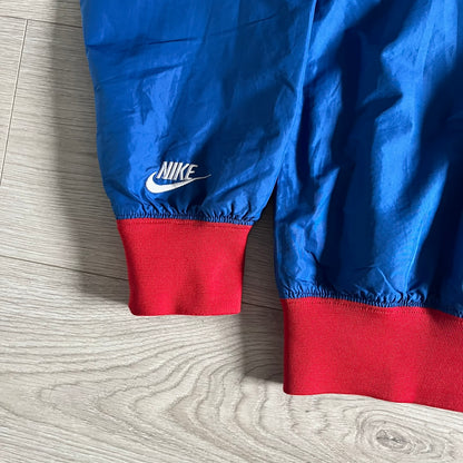 Nike UK Olympics 2008 Split Windbreaker designed by Jarrett Reynolds. Features a blue base with Union Jack-inspired red and white stripes on the front, representing Great Britain. Dual side zippers allow the jacket to be split in half and combined with other pieces from the collection, with a subtle United Kingdom flag inside the pocket.