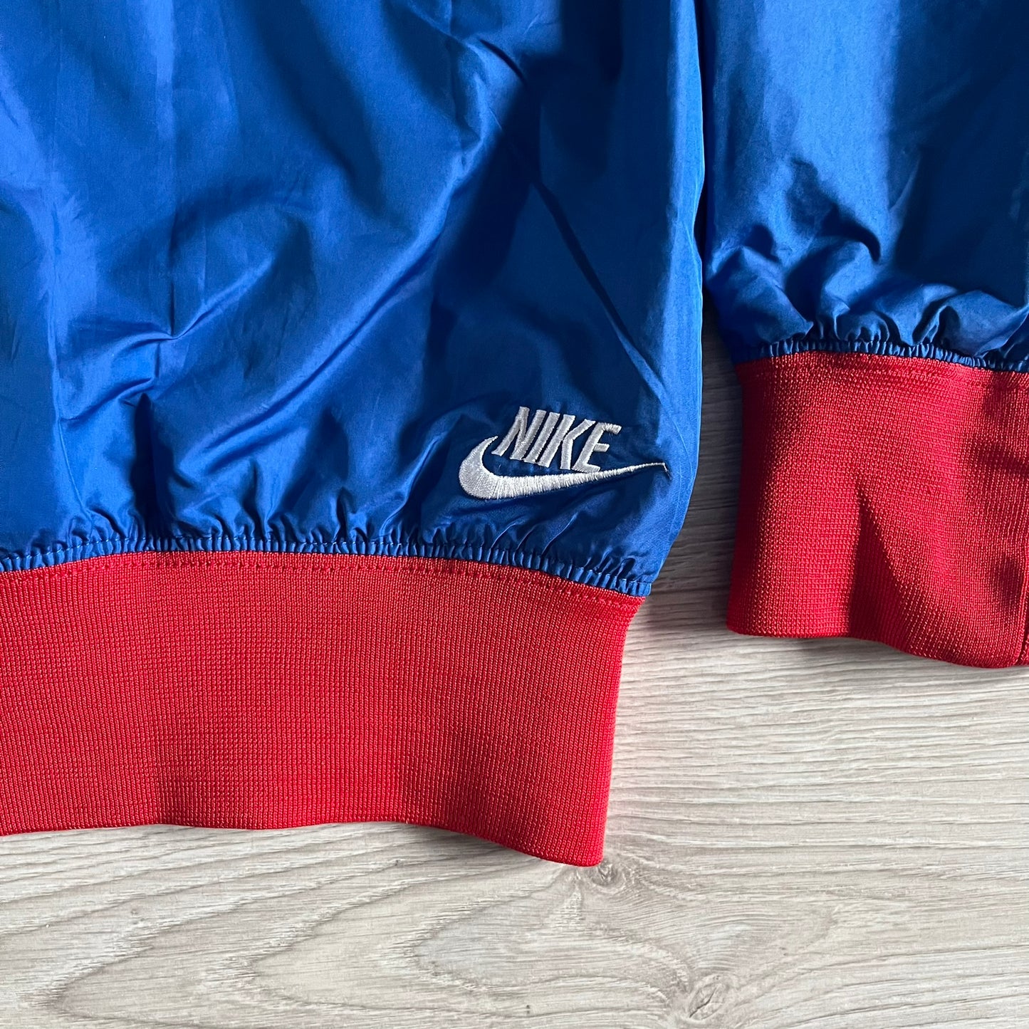 Nike UK Olympics 2008 Split Windbreaker designed by Jarrett Reynolds. Features a blue base with Union Jack-inspired red and white stripes on the front, representing Great Britain. Dual side zippers allow the jacket to be split in half and combined with other pieces from the collection, with a subtle United Kingdom flag inside the pocket.