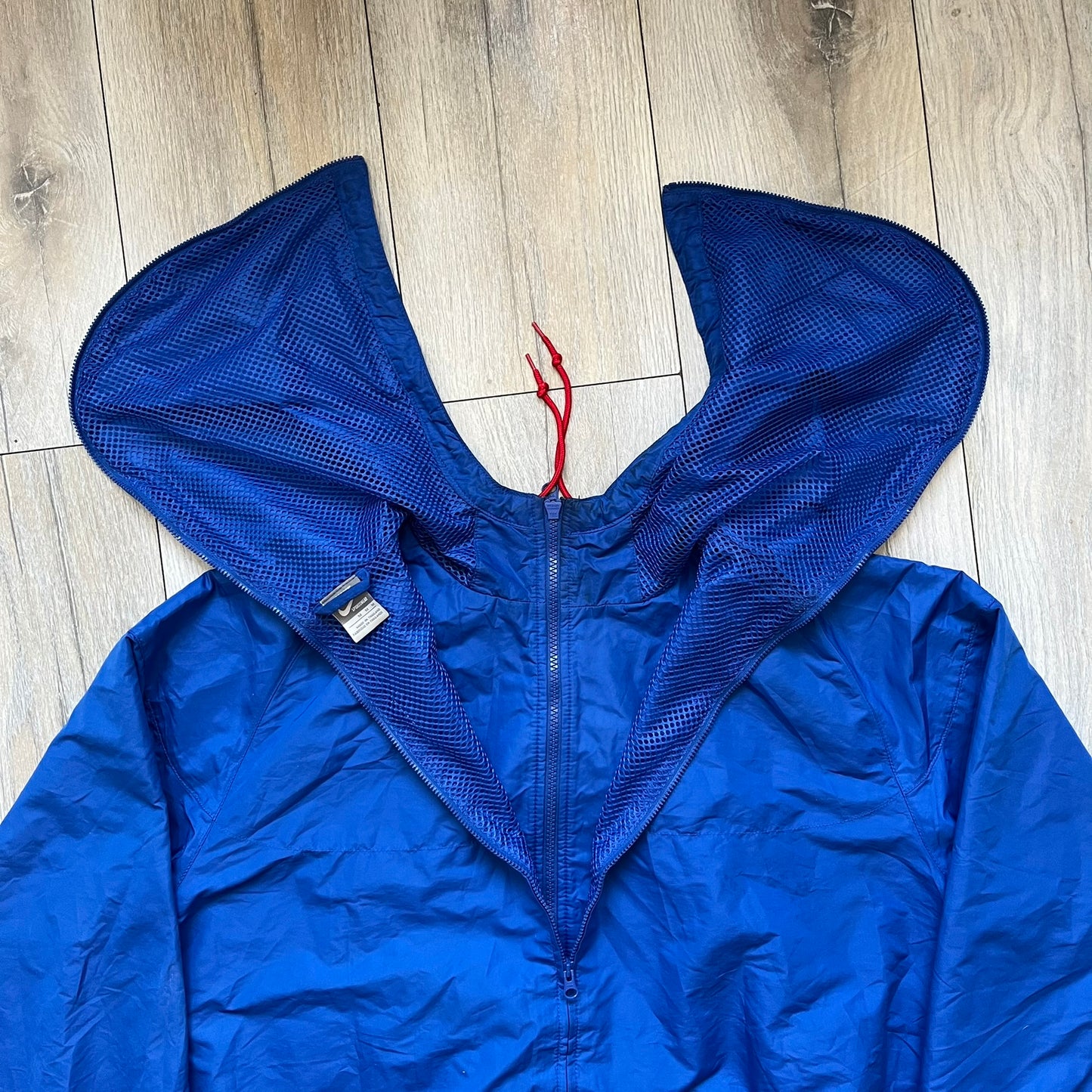 Nike UK Olympics 2008 Split Windbreaker designed by Jarrett Reynolds. Features a blue base with Union Jack-inspired red and white stripes on the front, representing Great Britain. Dual side zippers allow the jacket to be split in half and combined with other pieces from the collection, with a subtle United Kingdom flags inside the pocket.
