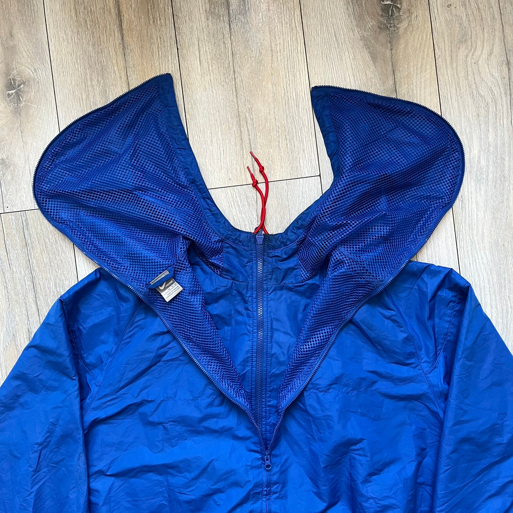 Nike UK Olympics 2008 Split Windbreaker designed by Jarrett Reynolds. Features a blue base with Union Jack-inspired red and white stripes on the front, representing Great Britain. Dual side zippers allow the jacket to be split in half and combined with other pieces from the collection, with a subtle United Kingdom flags inside the pocket.