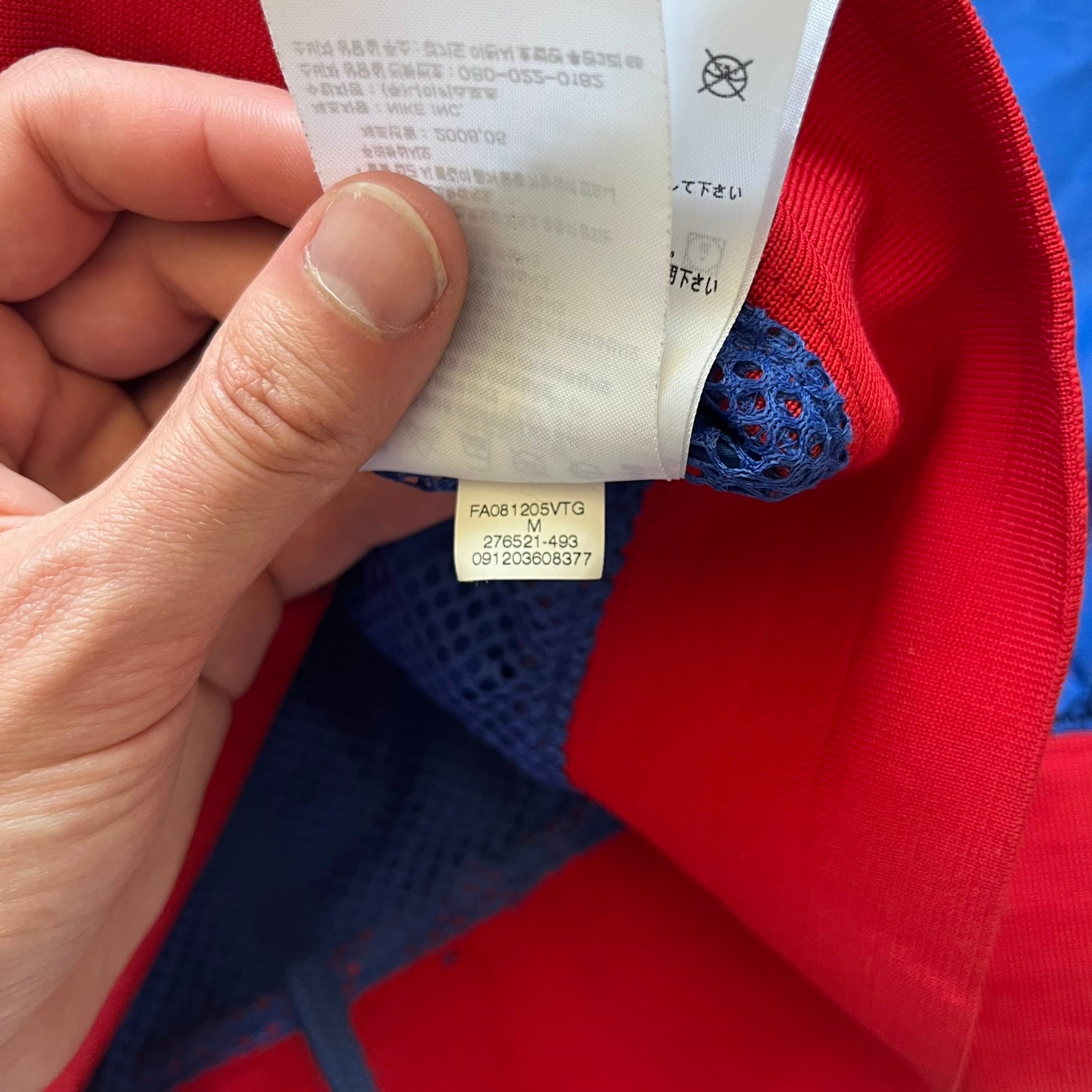 Nike UK Olympics 2008 Split Windbreaker designed by Jarrett Reynolds. Features a blue base with Union Jack-inspired red and white stripes on the front, representing Great Britain. Dual side zippers allow the jacket to be split in half and combined with other pieces from the collection, with a subtle United Kingdom flags inside the pocket.