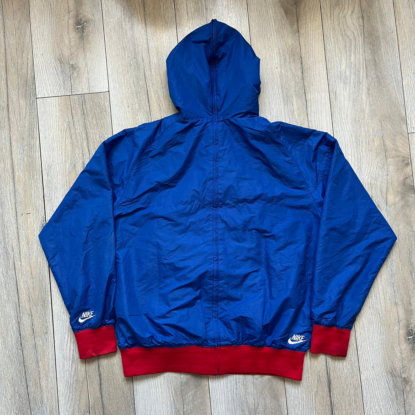 Nike UK Olympics 2008 Split Windbreaker designed by Jarrett Reynolds. Features a blue base with Union Jack-inspired red and white stripes on the front, representing Great Britain. Dual side zippers allow the jacket to be split in half and combined with other pieces from the collection, with a subtle United Kingdom flags inside the pocket.