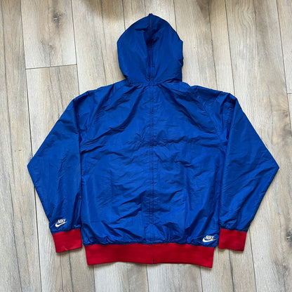 Nike UK Olympics 2008 Split Windbreaker designed by Jarrett Reynolds. Features a blue base with Union Jack-inspired red and white stripes on the front, representing Great Britain. Dual side zippers allow the jacket to be split in half and combined with other pieces from the collection, with a subtle United Kingdom flags inside the pocket.