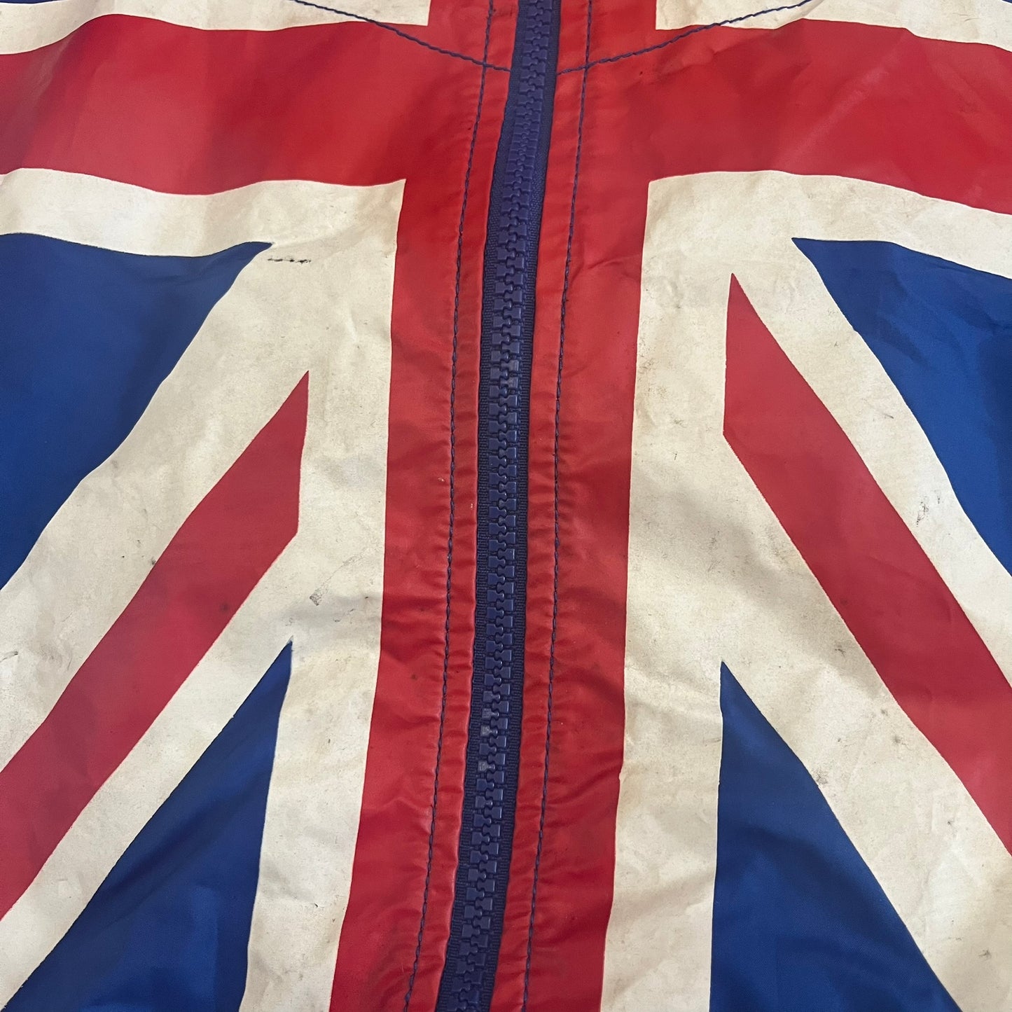 Nike UK Olympics 2008 Split Windbreaker designed by Jarrett Reynolds. Features a blue base with Union Jack-inspired red and white stripes on the front, representing Great Britain. Dual side zippers allow the jacket to be split in half and combined with other pieces from the collection, with a subtle United Kingdom flags inside the pocket.