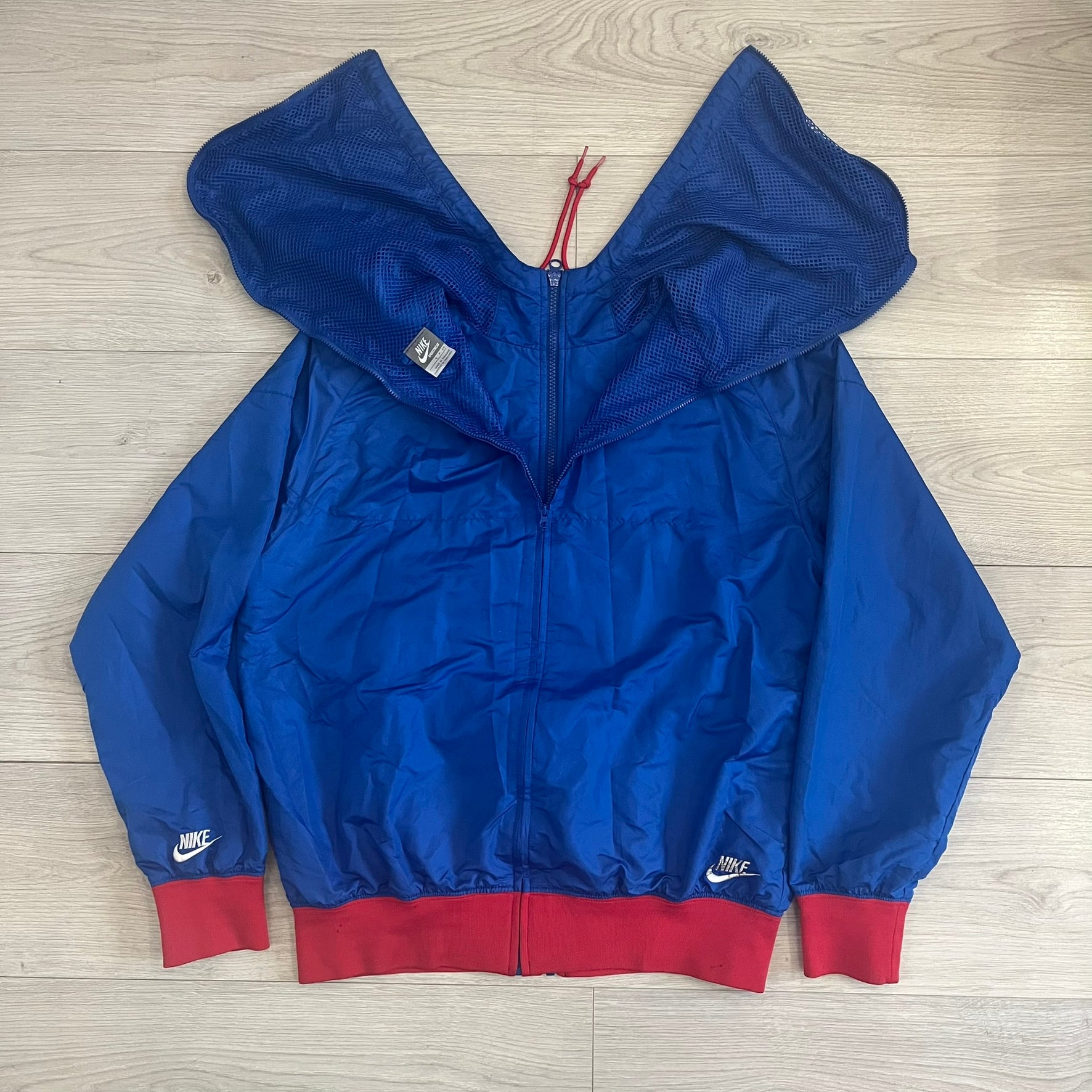 Nike UK Olympics 2008 Split Windbreaker designed by Jarrett Reynolds. Features a blue base with Union Jack-inspired red and white stripes on the front, representing Great Britain. Dual side zippers allow the jacket to be split in half and combined with other pieces from the collection, with a subtle United Kingdom flags inside the pocket.
