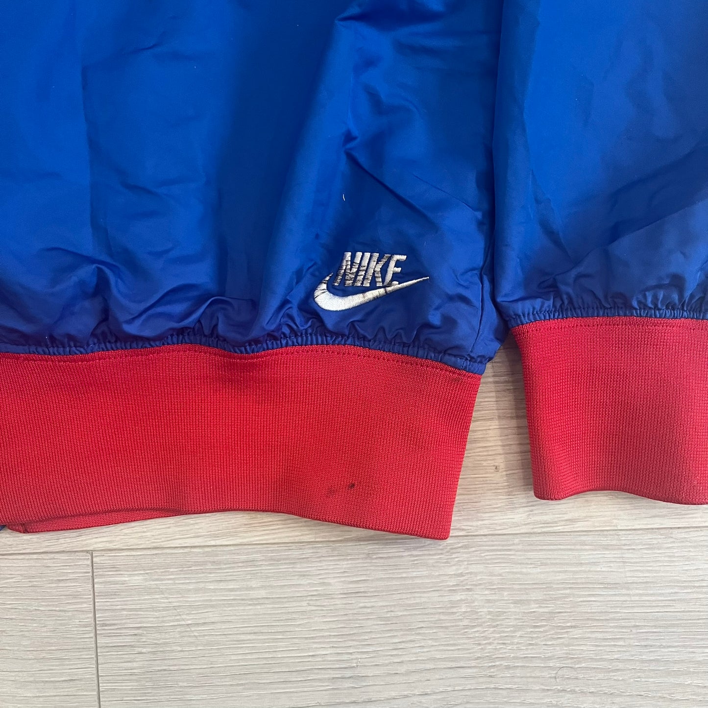 Nike UK Olympics 2008 Split Windbreaker designed by Jarrett Reynolds. Features a blue base with Union Jack-inspired red and white stripes on the front, representing Great Britain. Dual side zippers allow the jacket to be split in half and combined with other pieces from the collection, with a subtle United Kingdom flags inside the pocket.