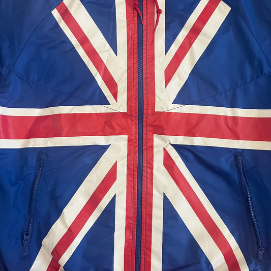 Nike UK Olympics 2008 Split Windbreaker designed by Jarrett Reynolds. Features a blue base with Union Jack-inspired red and white stripes on the front, representing Great Britain. Dual side zippers allow the jacket to be split in half and combined with other pieces from the collection, with a subtle United Kingdom flags inside the pocket.