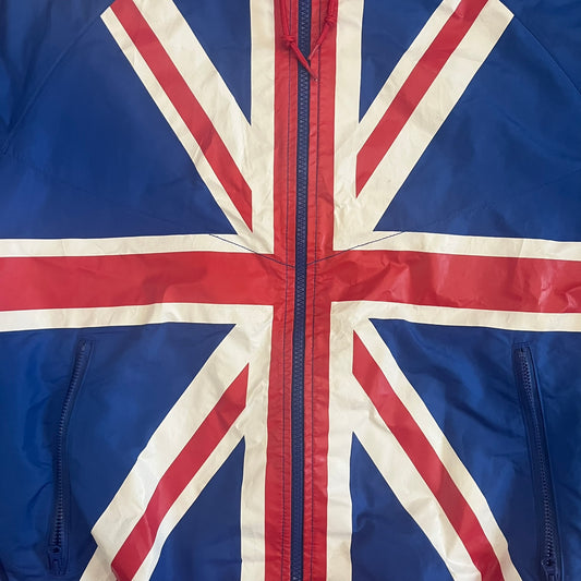 Nike UK Olympics 2008 Split Windbreaker designed by Jarrett Reynolds. Features a blue base with Union Jack-inspired red and white stripes on the front, representing Great Britain. Dual side zippers allow the jacket to be split in half and combined with other pieces from the collection, with a subtle United Kingdom flags inside the pocket.
