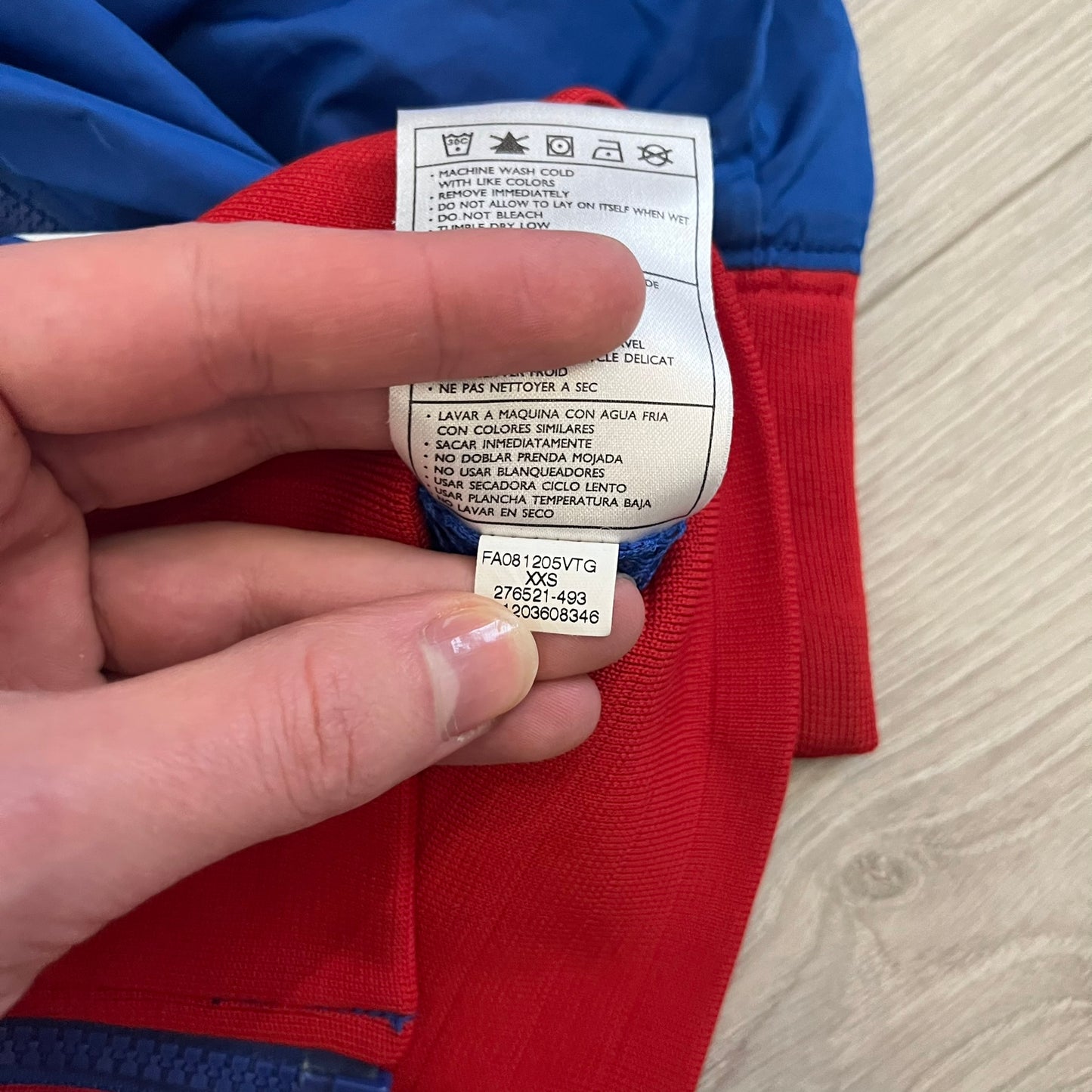 Nike UK Olympics 2008 Split Windbreaker designed by Jarrett Reynolds. Features a blue base with Union Jack-inspired red and white stripes on the front, representing Great Britain. Dual side zippers allow the jacket to be split in half and combined with other pieces from the collection, with a subtle United Kingdom flags inside the pocket.