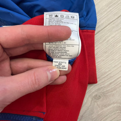 Nike UK Olympics 2008 Split Windbreaker designed by Jarrett Reynolds. Features a blue base with Union Jack-inspired red and white stripes on the front, representing Great Britain. Dual side zippers allow the jacket to be split in half and combined with other pieces from the collection, with a subtle United Kingdom flags inside the pocket.