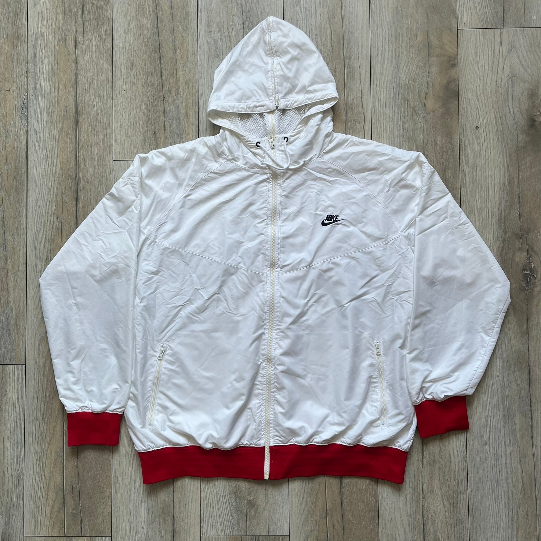 Nike United States (USA) Olympics Split Windbreaker from 2008, created by designer Jarrett Reynolds. Crafted in white, with red hems. Small Nike black embroidery on the chest and back. The upper half of the jacket have slightly visible stars all over. This innovative jacket can be zipped apart on both sides and merged with other compatible models. Hidden inside, a small USA flags accent completes the concept.