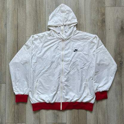 Nike United States (USA) Olympics Split Windbreaker from 2008, created by designer Jarrett Reynolds. Crafted in white, with red hems. Small Nike black embroidery on the chest and back. The upper half of the jacket have slightly visible stars all over. This innovative jacket can be zipped apart on both sides and merged with other compatible models. Hidden inside, a small USA flags accent completes the concept.