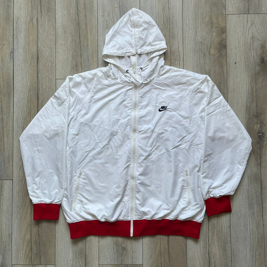 Nike United States (USA) Olympics Split Windbreaker from 2008, created by designer Jarrett Reynolds. Crafted in white, with red hems. Small Nike black embroidery on the chest and back. The upper half of the jacket have slightly visible stars all over. This innovative jacket can be zipped apart on both sides and merged with other compatible models. Hidden inside, a small USA flags accent completes the concept.