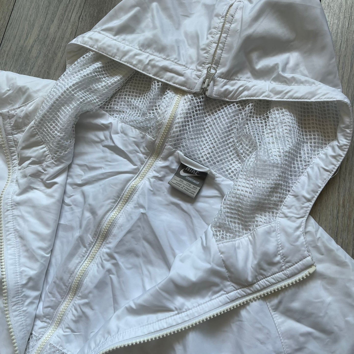 Nike United States (USA) Olympics Split Windbreaker from 2008, created by designer Jarrett Reynolds. Crafted in white, with red hems. Small Nike black embroidery on the chest and back. The upper half of the jacket have slightly visible stars all over. This innovative jacket can be zipped apart on both sides and merged with other compatible models. Hidden inside, a small USA flags accent completes the concept.