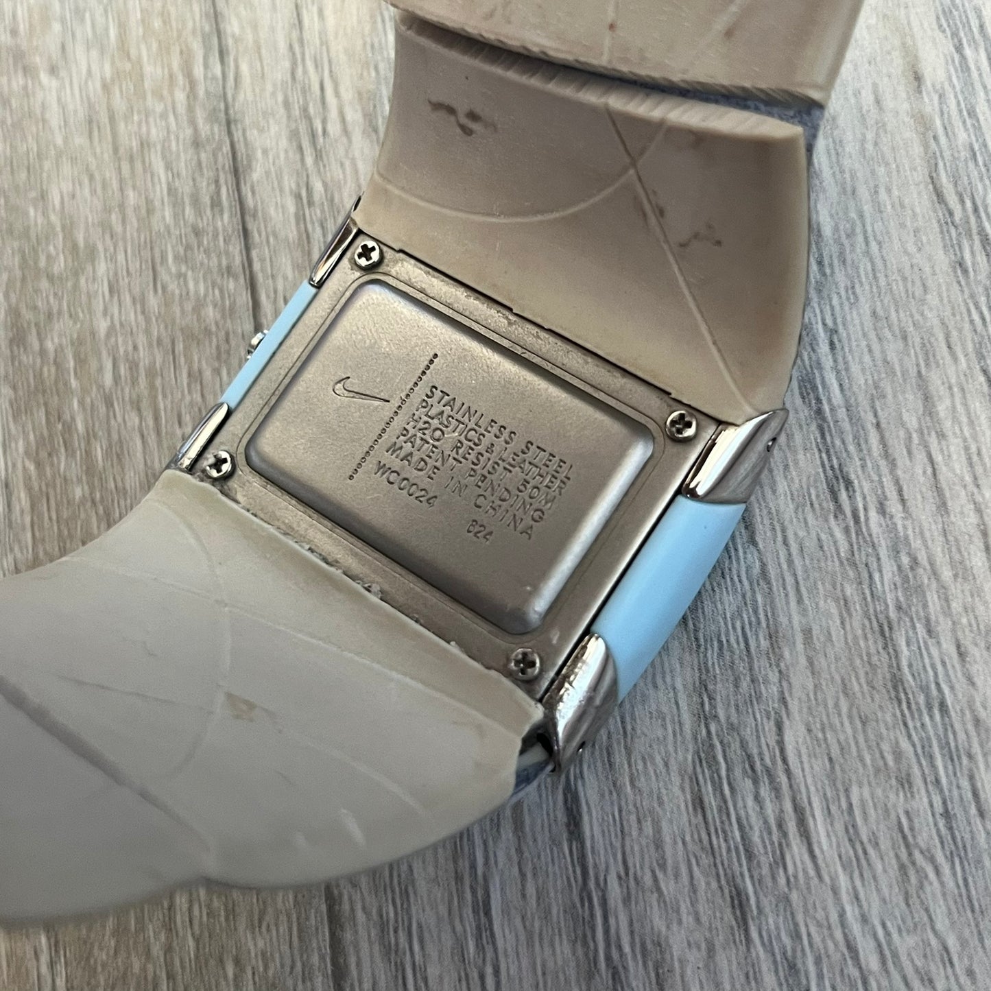 Nike WC0024-624 Merge Attract Baby Blue Digital Watch is a digital wristwatch featuring a silver-tone stainless steel case with a analog display. The straps are baby blue with engraved floral pattern graphics on the outer side and a beige inner lining, made from a combination of leather, plastic, and rubber materials. The dial is metallic baby blue with small dots pattern.